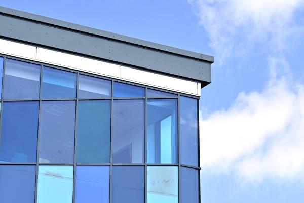 Building with different shades of blue glass windows, with blue sky behind