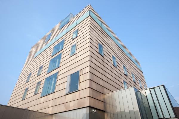 Exterior of the New Art Gallery Walsall, clad in pale terracotta tile with a steel and glass entrance