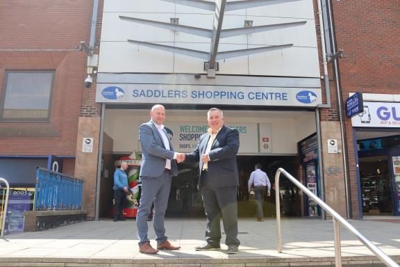 Councillor Adrian Andrew and Andy Ryan (Kier) shaking hands outside the entrance to the Saddlers Centre