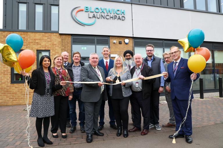 Walsall Mayor cutting a ribbon outside Bloxwich Launchpad, with a group of people holding balloons and smiling