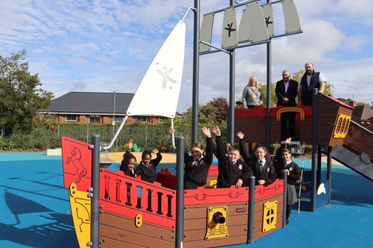 A group of children playing on a boat-shaped playpark