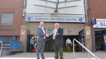 Councillor Adrian Andrew and Andy Ryan (Kier) shaking hands outside the entrance to the Saddlers Centre