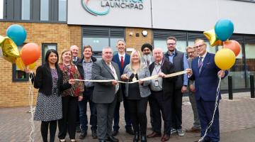 Walsall Mayor cutting a ribbon outside Bloxwich Launchpad, with a group of people holding balloons and smiling