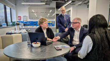 Four people sitting around a table and talking, inside Bloxwich Launchpad